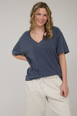 woman wearing a navy blue oversized v-neck t-shirt with loose cream sweatpants and smiling