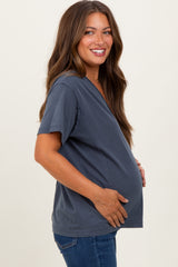 woman wearing a dark grey maternity top with short sleeves, holding her baby bump and smiling