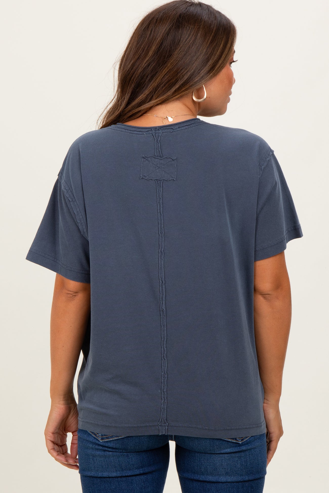 woman wearing a dark gray short sleeve maternity top with a relaxed fit and detailed stitching on the back