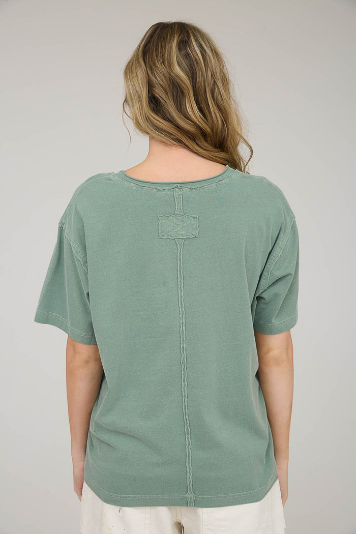 woman wearing a green oversized t-shirt with a relaxed fit and back stitch detail
