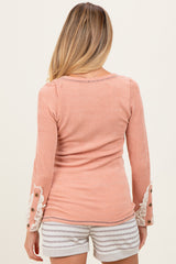 woman wearing a peach ribbed maternity top with lace details on the sleeves and a fitted silhouette