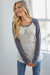 woman wearing a cream and navy long sleeve raglan top with a scoop neck and relaxed fit
