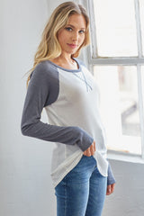 woman wearing a white and gray long sleeve raglan top with a relaxed fit and blue jeans