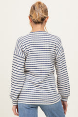 woman wearing a striped maternity sweater in cream and navy blue, showing the back view with loose fit and long sleeves