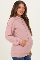 woman wearing a light pink ribbed maternity hoodie with a front pocket and a visible baby bump