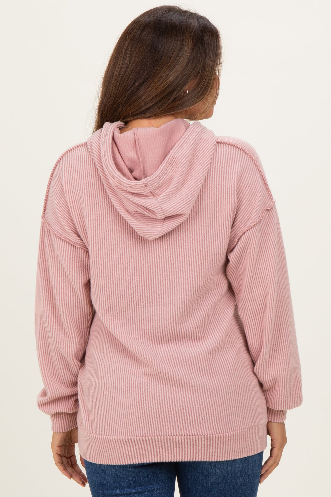 woman wearing a dusty pink ribbed hoodie, showing the back view, designed for maternity wear
