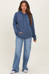 woman wearing a navy blue ribbed maternity hoodie with a front pocket and blue wide-leg jeans, showing her baby bump