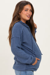 woman wearing a navy blue maternity hoodie with a textured design and side pockets, showing her baby bump