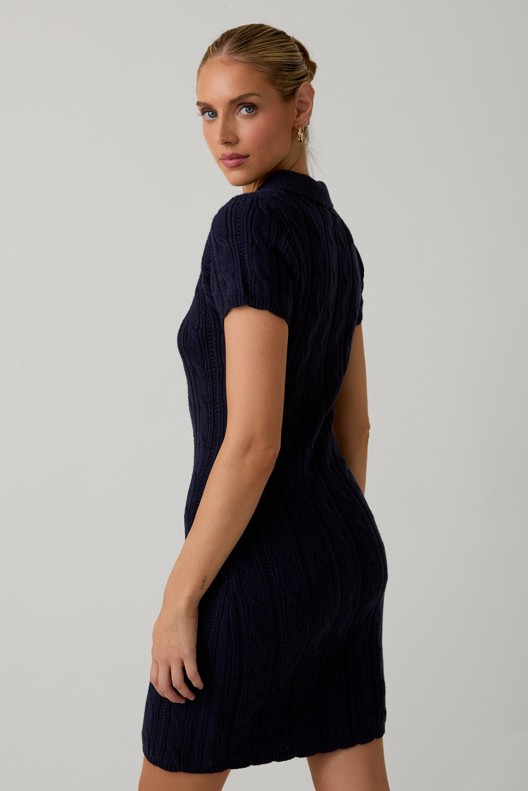 woman wearing a fitted navy blue short sleeve cable knit dress with a collared neckline