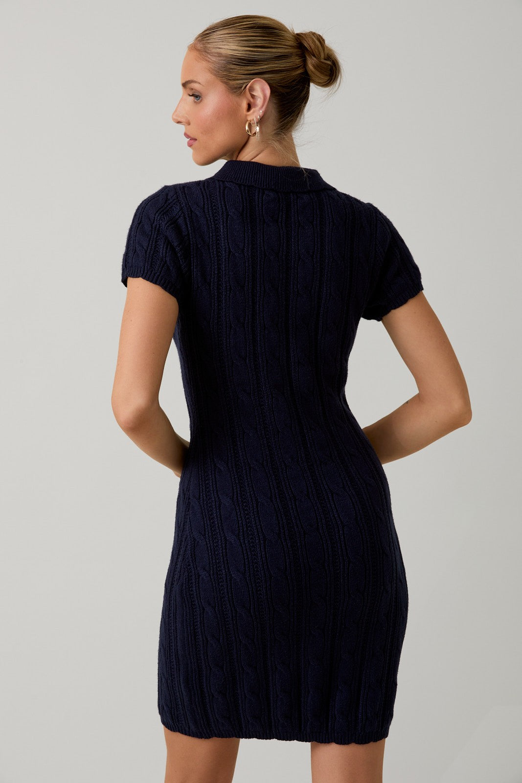 woman wearing a dark navy knitted short sleeve polo dress with a fitted silhouette