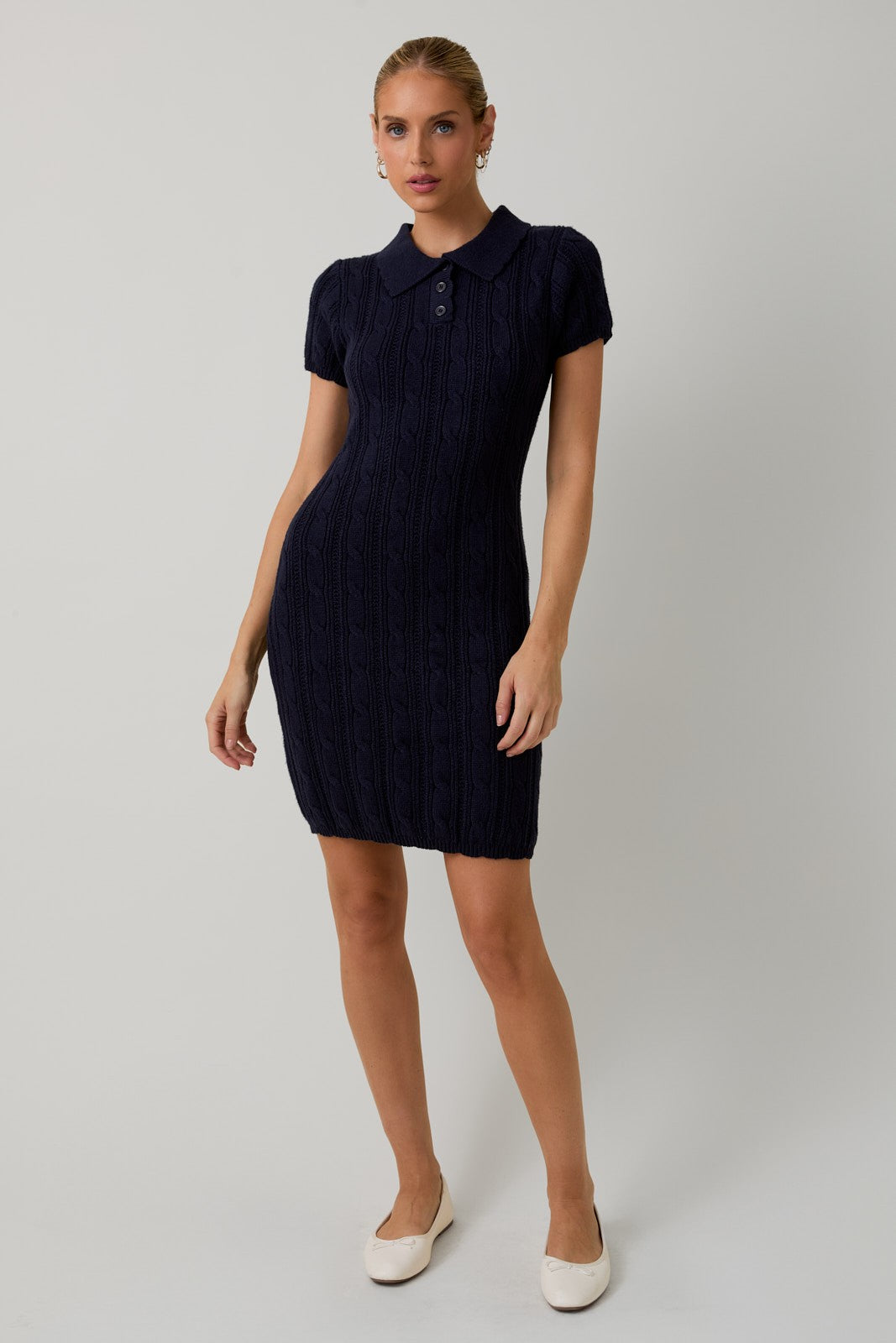 woman wearing a navy blue short sleeve polo dress with cable knit pattern and a fitted silhouette