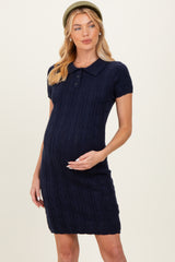 woman wearing a navy knitted short sleeve polo maternity dress and holding her baby bump
