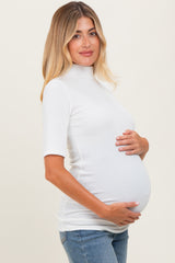 woman wearing a white ribbed maternity top and holding her baby bump