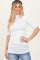 woman wearing a white ribbed short sleeve top and blue jeans, smiling and posing with hands on hips