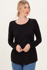 woman wearing a black long sleeve top with a fitted waist and relaxed fit, standing and looking to the side