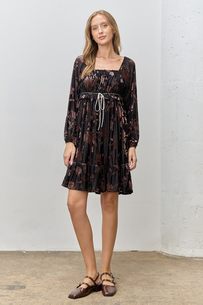 woman wearing a black floral print short dress with puff sleeves and a tied waist detail