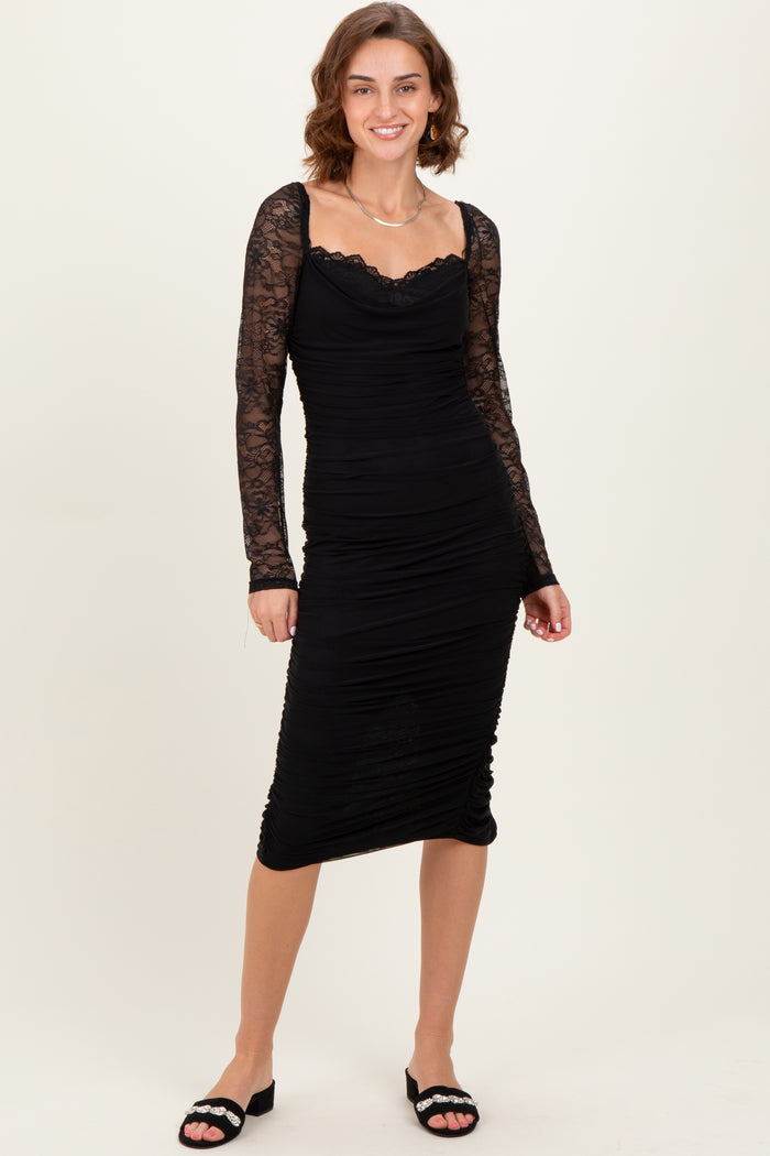woman wearing a black ruched midi dress with lace long sleeves and a sweetheart neckline
