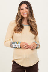 woman wearing a yellow ribbed maternity top with patterned sleeves and a visible baby bump