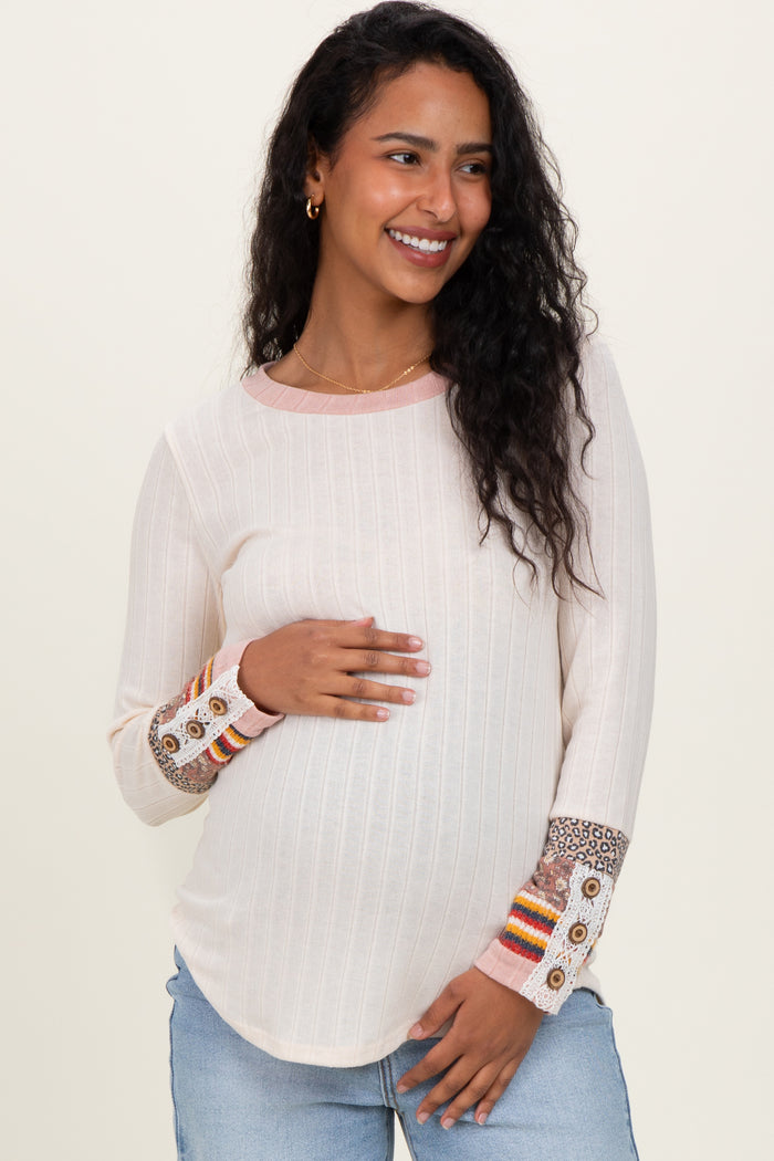 woman wearing a cream long sleeve maternity top with colorful patterned cuffs and showing her baby bump