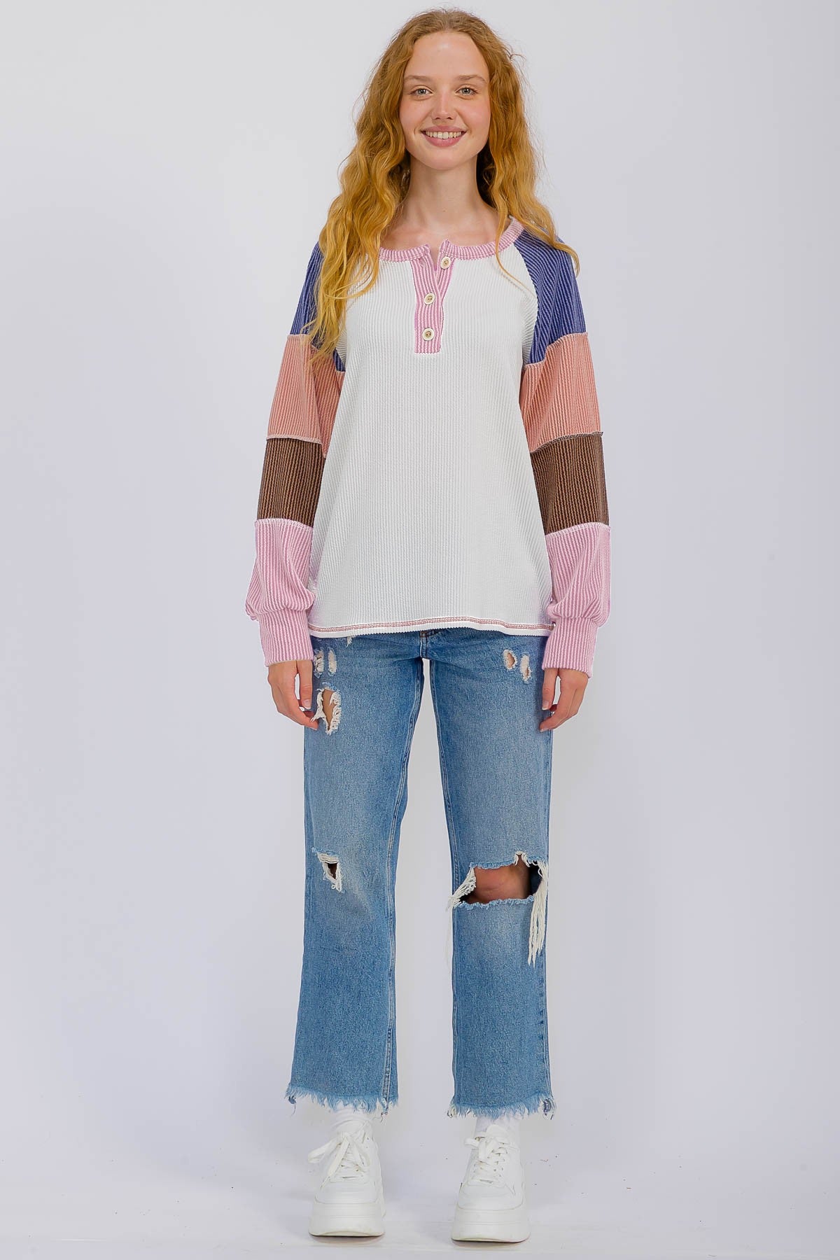 woman wearing a multi-colored long sleeve button-up top with a sporty style and distressed blue jeans
