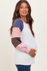 woman wearing a color block maternity top with button details, showing her baby bump