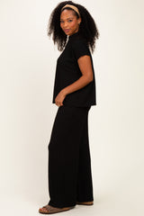 woman wearing a black ribbed short sleeve top and black wide-leg pants