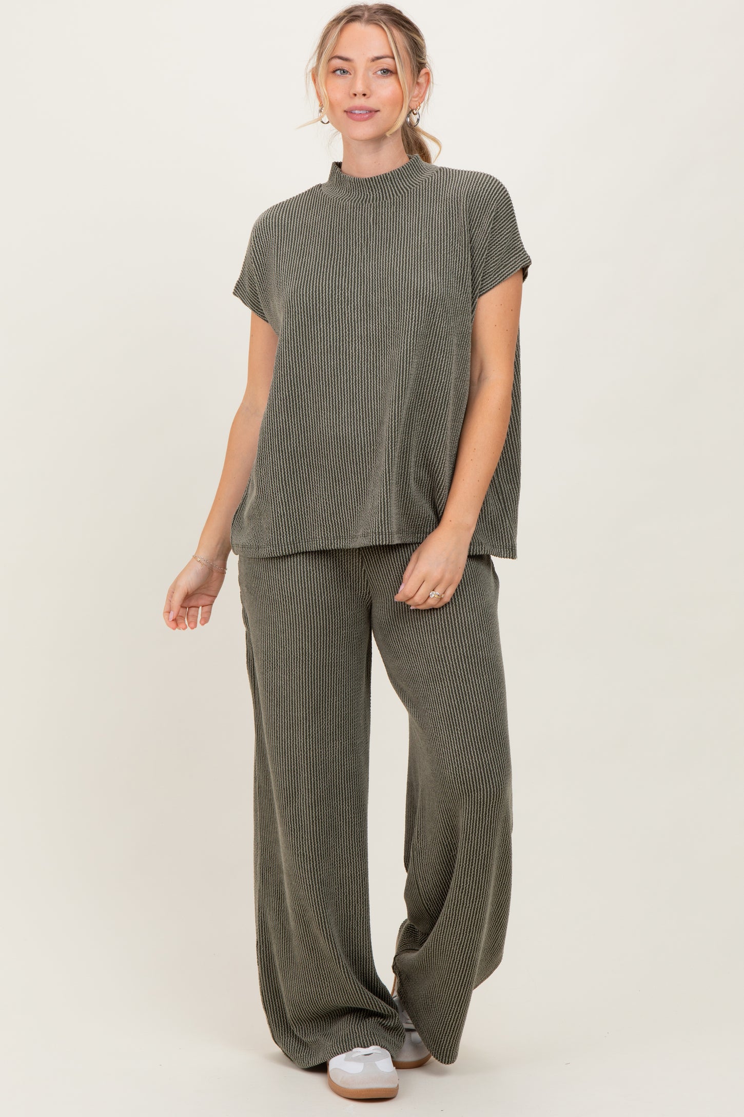 woman wearing a ribbed olive green short sleeve top and matching wide-leg pants, standing against a neutral background