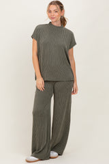 woman wearing a green striped short sleeve top and matching wide-leg pants, smiling against a neutral background