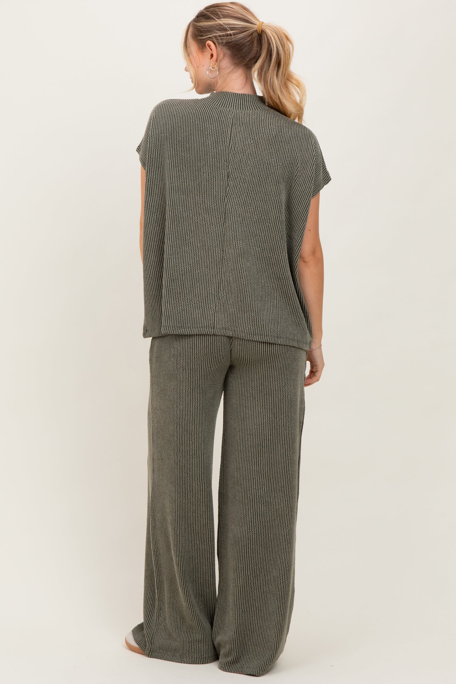 woman wearing a sage green striped two-piece lounge set with short sleeves and wide-leg pants