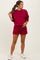 woman wearing a burgundy maternity sweatshirt and matching shorts, showing a baby bump and styled with white sneakers