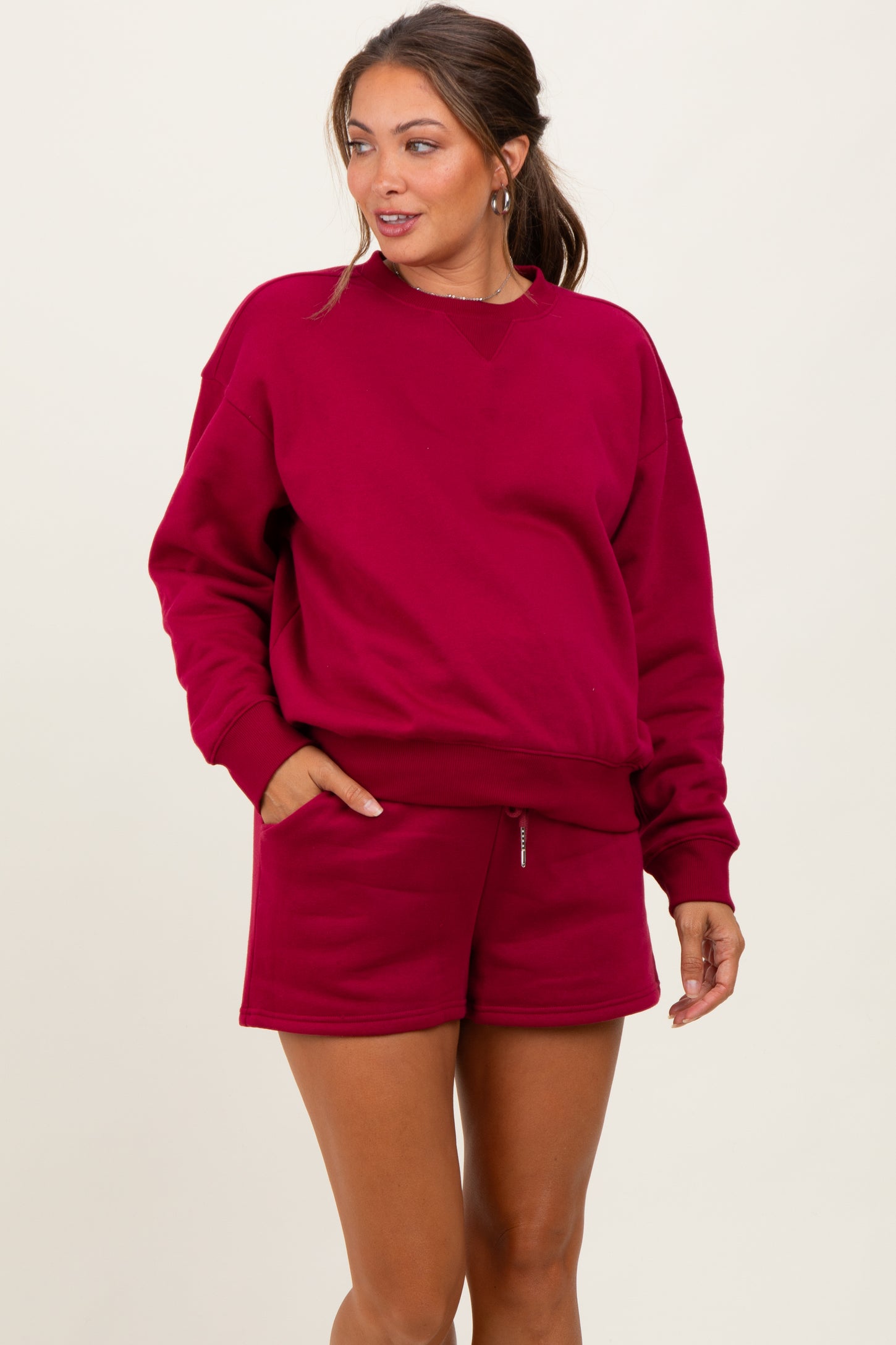woman wearing a burgundy maternity sweatshirt and matching shorts, showing her baby bump