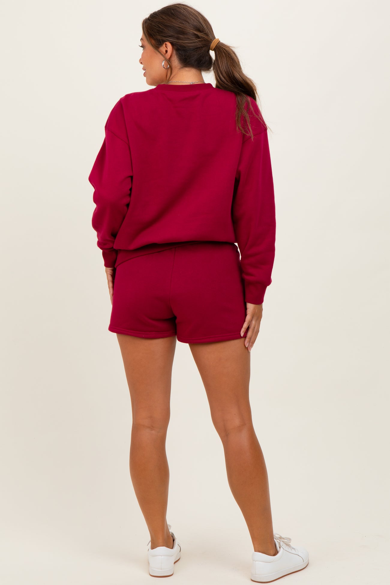 woman wearing a burgundy maternity sweatshirt and matching shorts, showing a baby bump from the back