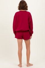 woman wearing a burgundy oversized sweatshirt and matching shorts, viewed from the back