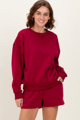 woman wearing a burgundy oversized sweatshirt with long sleeves and matching shorts