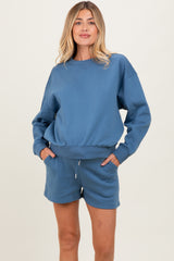 woman wearing a blue maternity sweatshirt and matching shorts with pockets