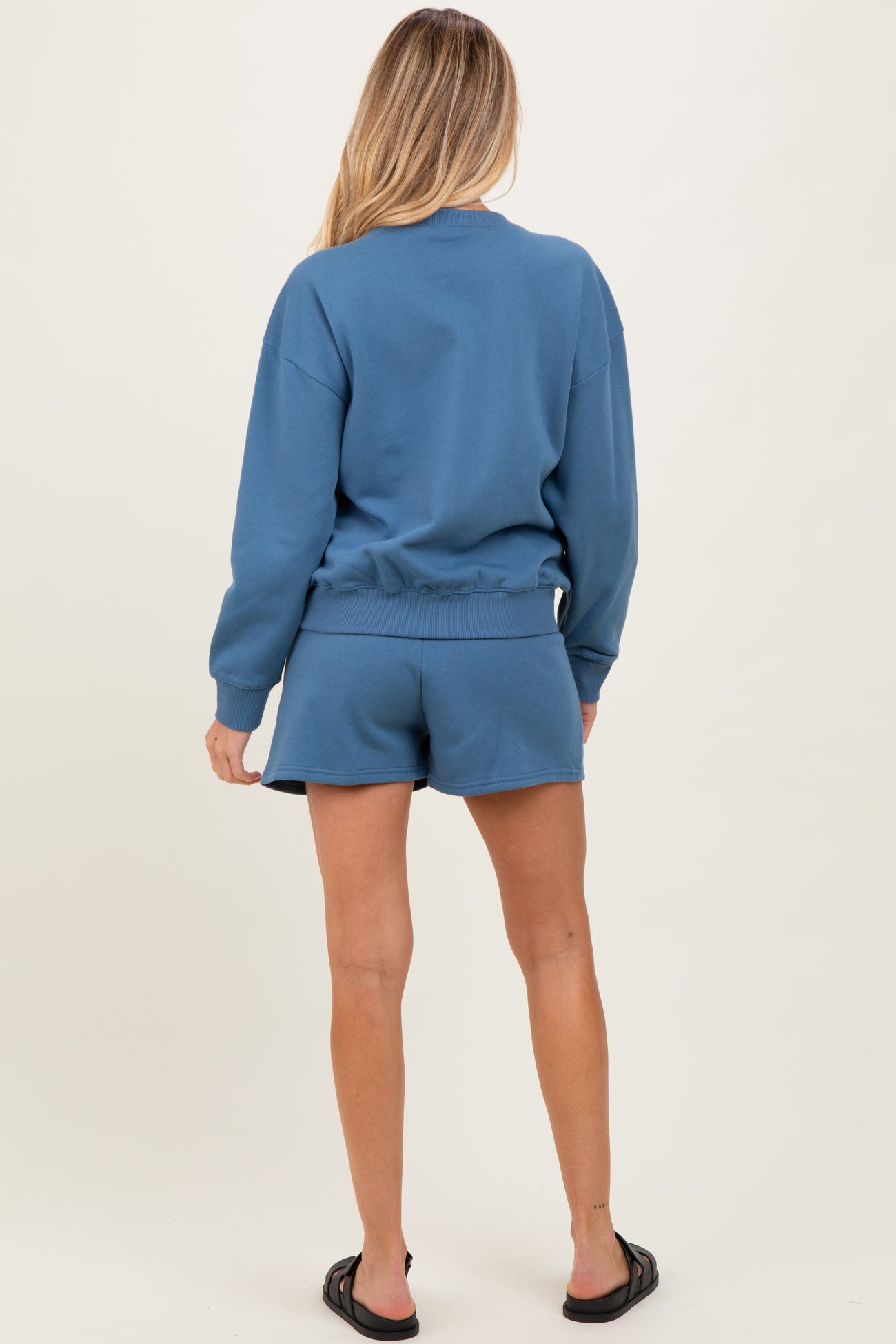 woman wearing a blue maternity sweatshirt and matching shorts, showing a relaxed fit and comfortable style