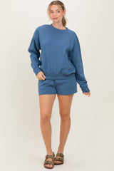 woman wearing a blue sweatshirt and matching shorts, styled casually with a relaxed fit and drawstring waist