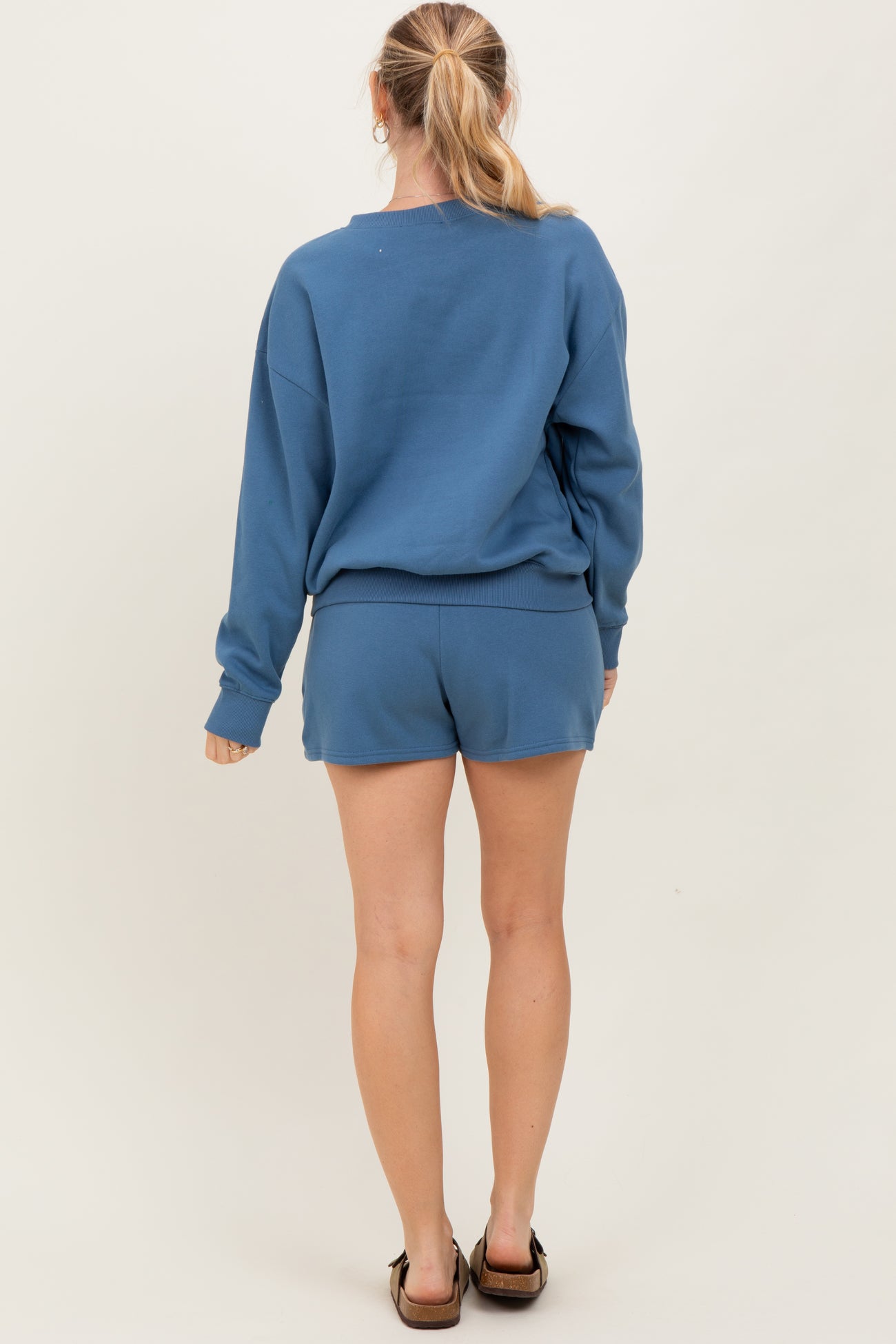 woman wearing a blue oversized sweatshirt and matching shorts, viewed from the back