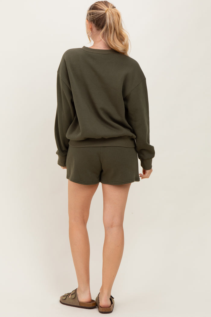 woman wearing an olive green oversized sweatshirt and matching shorts, seen from the back