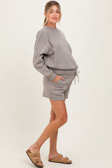woman wearing a grey maternity sweatshirt and matching shorts, with a relaxed fit and drawstring waist