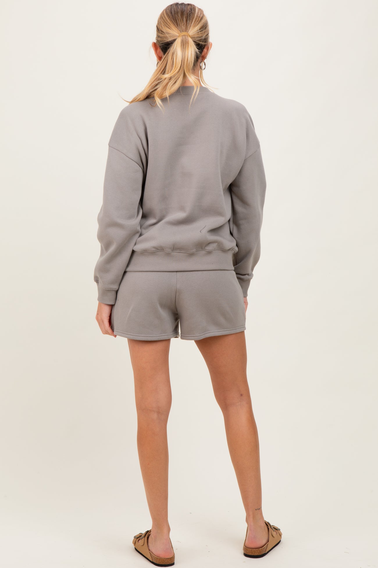 woman wearing a gray maternity sweatshirt and shorts, showing her back and a relaxed fit