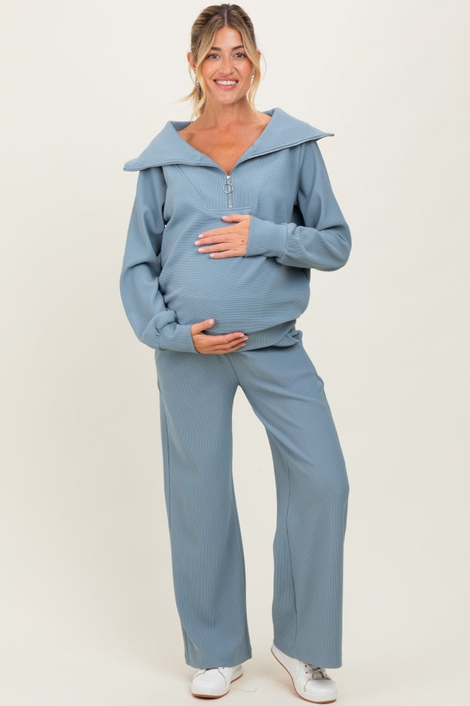 woman wearing a light blue maternity tracksuit with a zip-up top and wide-leg pants, showcasing her baby bump