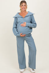 woman wearing a light blue maternity tracksuit with a zip-up top and wide-leg pants, showcasing her baby bump