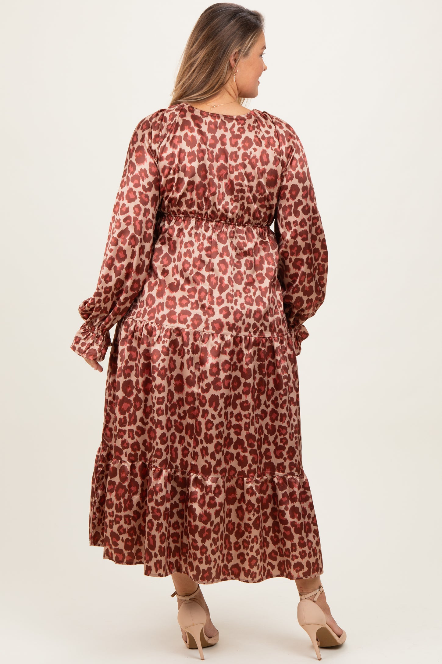 woman wearing a brown leopard print maternity dress with long sleeves and tiered skirt, showcasing her baby bump from the back