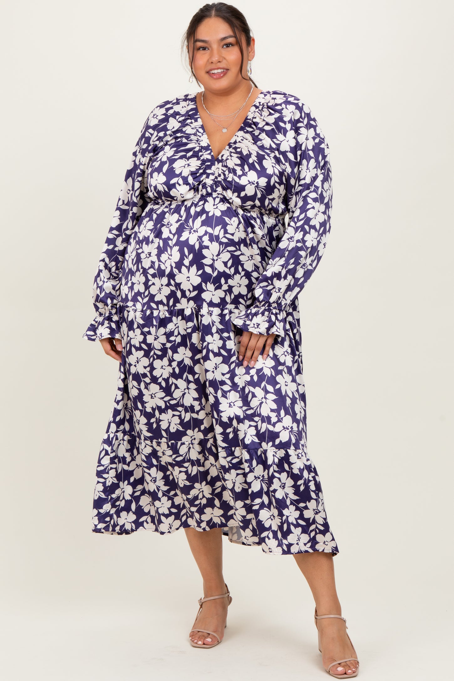 woman wearing a purple floral long sleeve plus size dress with a v-neckline and tiered skirt