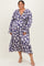 woman wearing a purple floral long sleeve plus size dress with a v-neckline and tiered skirt