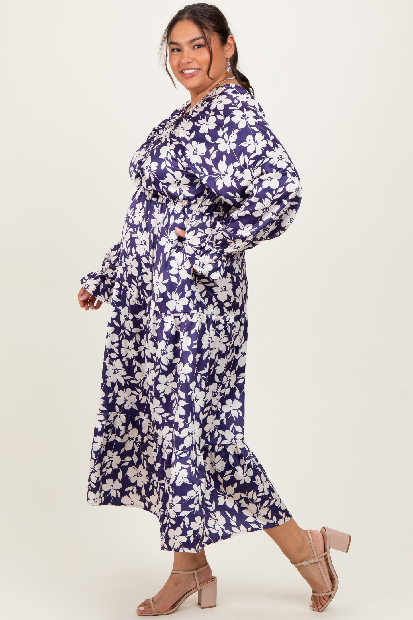 woman wearing a floral print long sleeve maxi dress in purple with a cinched waist and ruffled details