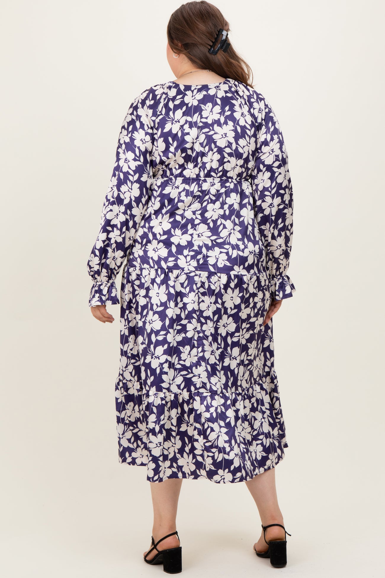 woman wearing a floral print long sleeve maternity plus dress with a tiered skirt, showing the back view