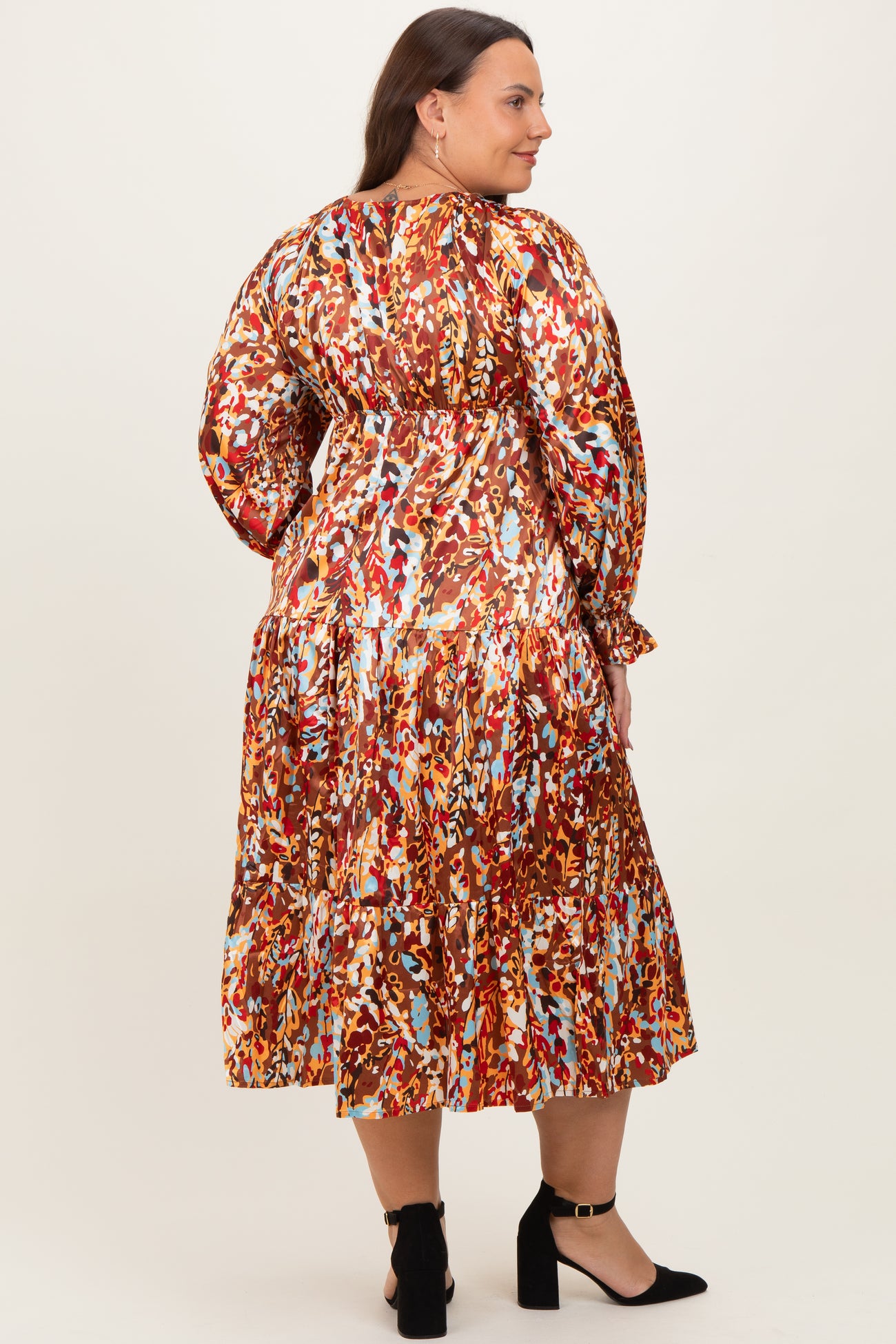 plus size woman wearing a colorful printed long sleeve maxi dress with a gathered waist and tiered skirt