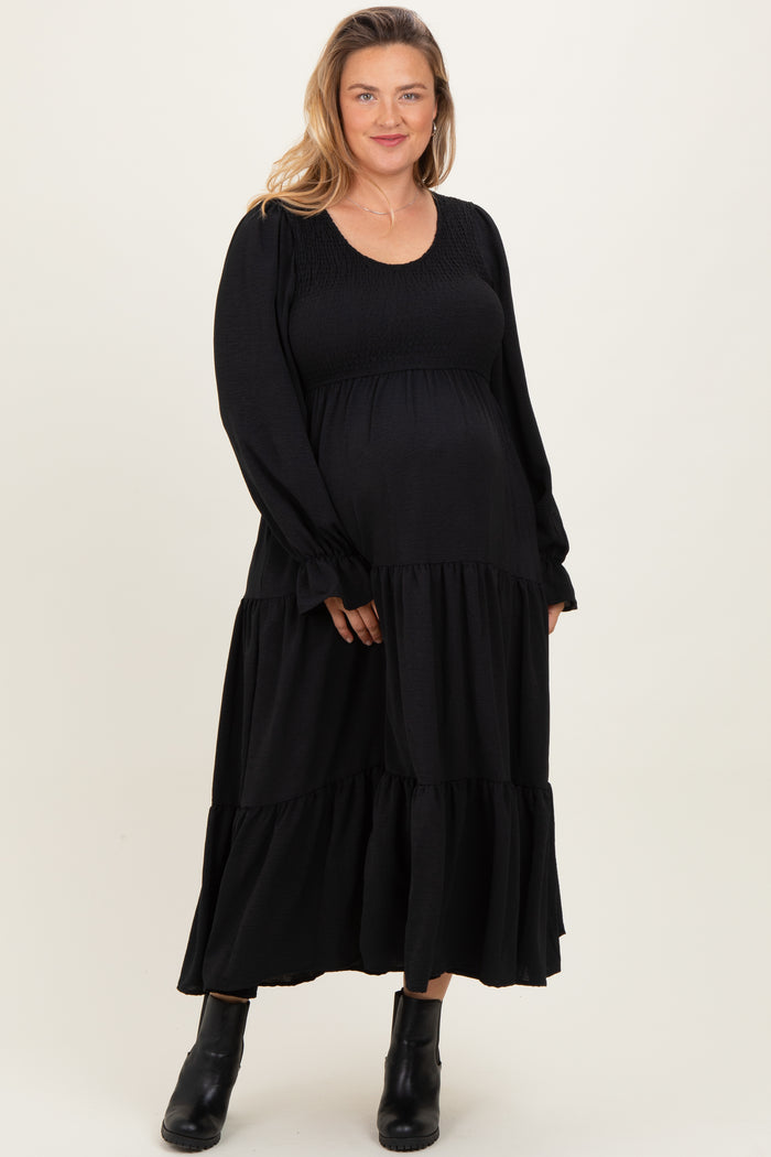 woman wearing a black long sleeve maternity dress with tiered skirt and a visible baby bump